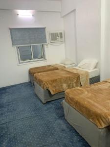a room with three beds and a window at Al Awali Economic Apartments in Al Madinah