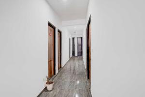 Collection O Sector 121 Gaur City Mall Noida Royal FNG في نويدا: ممر بجدران بيضاء وأرضيات خشبية وممر به أبواب