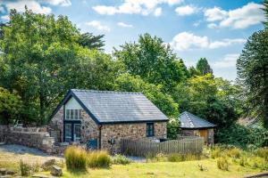 un cottage in pietra con un tetto in ardesia di The Old Smithy - 2 Bedroom Cottage - Reynoldston a Reynoldston