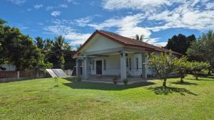 a small white house with a grass yard at Merbok Little Bungalow in Kampong Merbok
