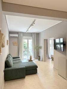 a living room with a green couch and a tv at Acropolis Path - Elegant Apartment near Plaka in Athens