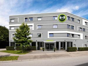 a large white building with a green sign on it at B&B Hotel Hamburg-Harburg in Hamburg