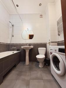 a bathroom with a toilet sink and a washing machine at Kyiv Sofia Apartment in Kyiv