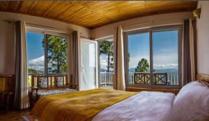 a bedroom with a large bed and large windows at Kasar Rainbow Yoga Retreat in Hawālbāgh