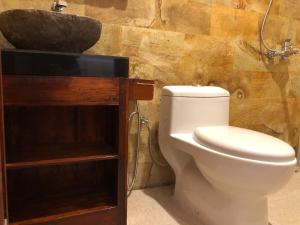a bathroom with a white toilet and a sink at Pondok Kakiang in Pulukan +28 photos