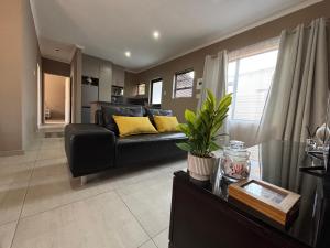 sala de estar con sofá negro y almohadas amarillas en Matusadona Suites, en Mokopane