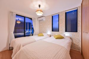 two beds in a room with two windows at Hotel Tsunagari 2 in Fukuoka