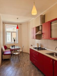 a kitchen with red cabinets and a table with chairs at Kyiv Sofia Apartment in Kyiv