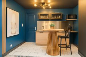 a kitchen with blue walls and a table and chairs at La Secrète, balnéo 50 nuances de grey in Roubaix
