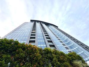a tall glass building with trees in front of it at Aeon Towers Davao Condotel near Abreeza Ayala Mall in Davao City