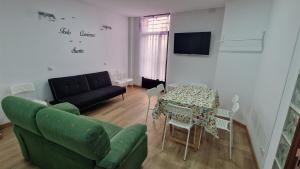 Serranos Salamanca Centro في سلامنكا: غرفة معيشة مع أريكة خضراء وطاولة