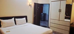 a bedroom with a white bed and a closet at Calangute Square by Ananta in Calangute