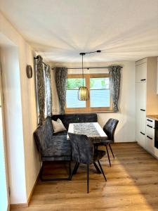 Un comedor con mesa y sillas y una ventana. en Apart Anton, en Hainzenberg