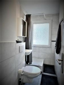 a white bathroom with a toilet and a window at Work Inn Rhein Ruhr Appartement in Duisburg