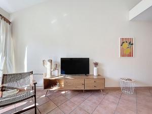 a living room with a television on a wooden cabinet at Les Colonnes - Appartement en duplex - Wifi in Narbonne +3 photos