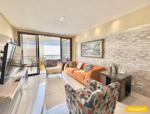 a living room with an orange couch and a brick wall at Mandara Lanai Resort - Porto das Dunas in Aquiraz
