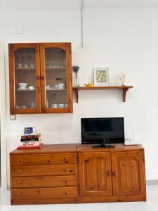 d'une armoire en bois avec une télévision. dans l'établissement Peñiscola apartamento con piscina, barbacoa y wifi, à Peñíscola