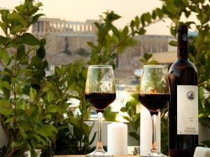 two glasses of red wine next to a bottle of wine at Athens View Loft - 03 in Athens