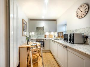 a kitchen with white cabinets and a clock on the wall at The Holly Tree Cottage in Rashfield
