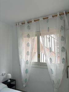 - une chambre avec des rideaux blancs et une fenêtre dans l'établissement Peñiscola apartamento con piscina, barbacoa y wifi, à Peñíscola