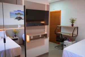 een hotelkamer met een tv en een bed bij Hotel & Pousada Porto Ubá in Lidianópolis