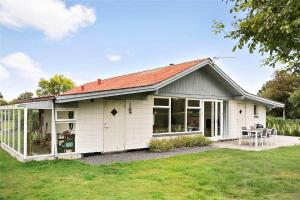 a white shed with a table and chairs in a yard at N242-Karrebaeksminde-Kildeengen-44 in Enø By