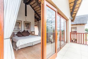 ein Schlafzimmer mit einem Bett und einem Balkon in der Unterkunft Waterberg House at Zebula - 8 adults and 4 kids under 10 years in Mabula