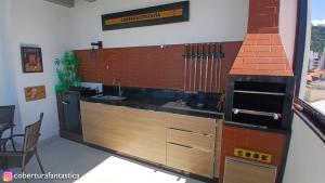 a kitchen with a counter with a sink and a stove at Fantástica cobertura apenas 70 metros da praia in Governador Celso Ramos