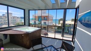 a room with a bath tub and a large window at Fantástica cobertura apenas 70 metros da praia in Governador Celso Ramos