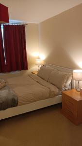 a bedroom with a bed with two lamps and a window at Spacious Cheltenham Flat with Free Allocated Parking in Cheltenham