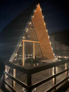 a house with a large window on a deck at night at A Frame Halmeag in Hălmeag