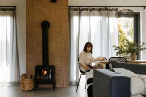 a woman sitting at a table in a living room with a fireplace at BURSZTYNOWA-PRZYSTAŃ in Lubiatowo
