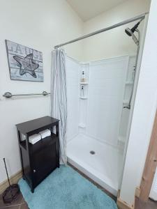 a white bathroom with a shower with a black table at Carlene's Place in Kingston