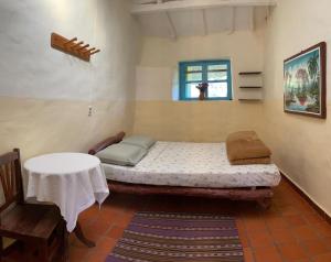 a room with a bed and a table and a window at El Jardin in Samaipata