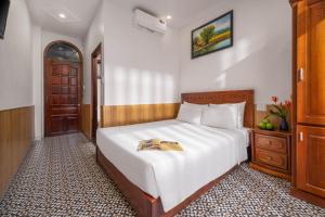 a bedroom with a bed with a book on it at Sala Hoi An Hotel in Hoi An