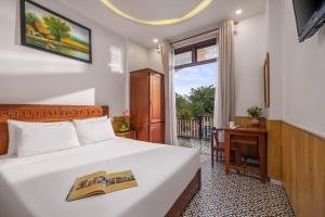 a bedroom with a bed and a desk and a window at Sala Hoi An Hotel in Hoi An