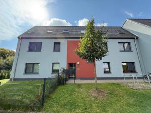 a white and red house with a tree in the yard at TT Living Apartment Schwarzenbek I 2 Zimmer I 4 Betten I Balkon I TG-Stellplatz in Schwarzenbek