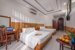 a bedroom with two beds and a desk with a computer at Sala Hoi An Hotel in Hoi An