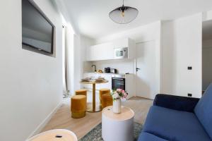 a living room with a blue couch and a kitchen at Résidence Saint Charles - Paris Expo in Paris