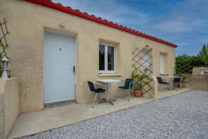 a table and chairs in front of a building with a door at Logis hôtel restaurant Le clos saint loup in Bram