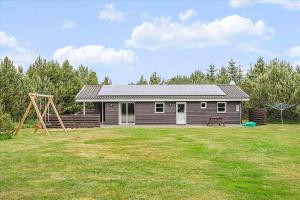 uma pequena casa com um parque infantil num quintal em JB699-Fjerritslev-Revlingestien-43 em Torup Strand