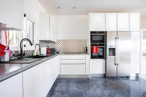 a kitchen with white cabinets and a refrigerator at Modern Panoramic Villa with Pool & Terrace in Puerto de la Cruz