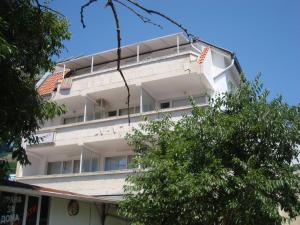 a white apartment building with a tree in front of it at Familia Fantastiko - Family Hotel in Kiten