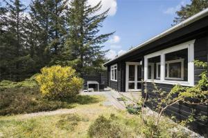 a black house with a white window and a yard at JB988-Fjerritslev-Skovstien-6 in Torup Strand