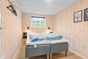 Bett in einem Zimmer mit Holzwänden und einem Fenster in der Unterkunft JB164 Fjerritslev - Poppelvej 16 in Fjerritslev