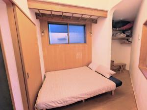 a small bed in a small room with a window at Asukayama Forrest in Tokyo