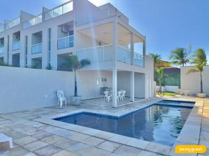 a house with a swimming pool in front of a house at Beach Townhouses IV in Mangabeira