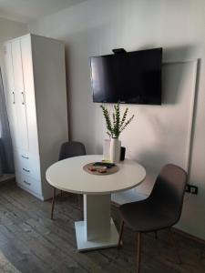 a white table with two chairs and a tv on a wall at Lu-Lu room in Požega