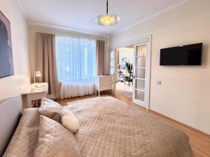 a bedroom with a large bed and a television at Elegant and bright flat in a quiet area in Rīga
