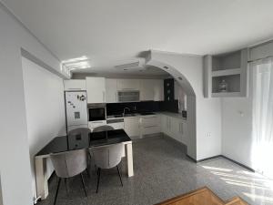a kitchen with white cabinets and a table and chairs at Apartman Centar comfort in Posušje